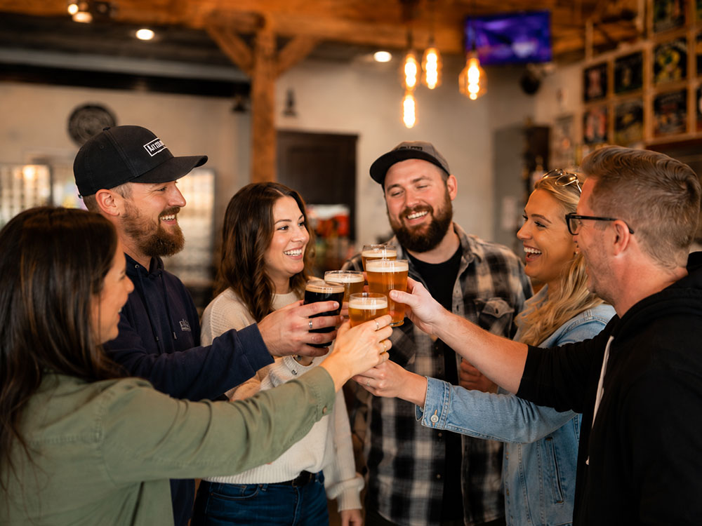 A group of friends cheers with glasses of beer while enjoying drinks together in a brewery.