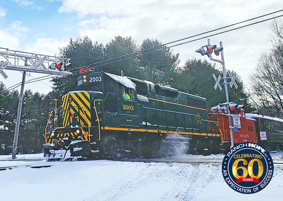 Image of desiel locomotive moving through a small town with snow. Alloway Ranch Hope Holiday Express featured image